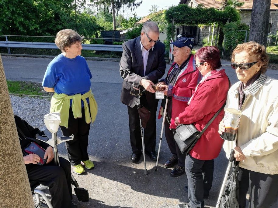 Skupina Starejsih Na Prostem Nekateri Imajo Bele Palice In Tipajo Manjse Etnoloske Predmete